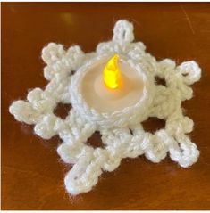 a crocheted candle holder with a lit candle in it