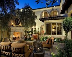 an outdoor living area with chairs, tables and fire place in front of a house