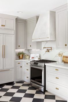 a kitchen with white cabinets and black and white checkered flooring on the floor