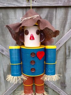 a tin can scarecrow hanging from a wooden fence