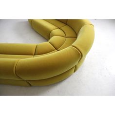 a yellow curved couch sitting on top of a white floor