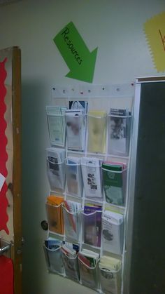 a bulletin board with several file folders and an arrow on the wall above it