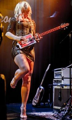 a woman is playing guitar on stage