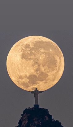 the full moon is seen over a hill