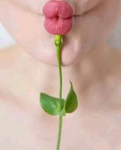 a woman's lips are sticking out from behind a flower