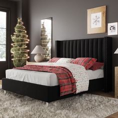 a bed room with a neatly made bed and a christmas tree