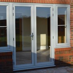 an image of a white double doors with brick wall and windows in the back ground