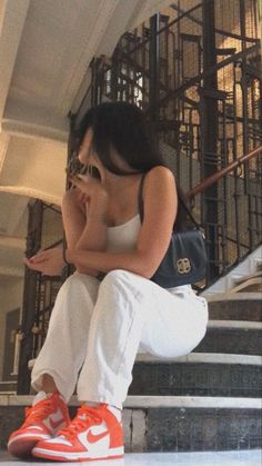 a woman sitting on the steps with her hand in her mouth