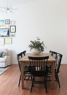 a dining room table with black chairs and a potted plant on top of it