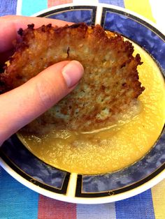 a person is holding up some food in a bowl on top of a blue and white plate