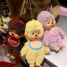 three little dolls are hanging from a purse on a table in front of other items