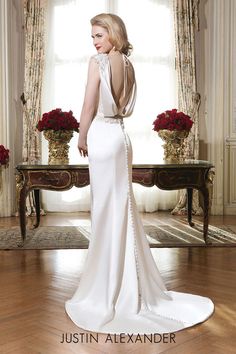 a woman standing in front of a table wearing a white dress with an open back