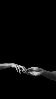 two hands reaching out towards each other in black and white, against a dark background