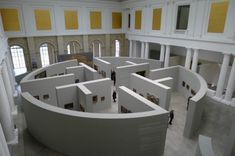 people are standing in the middle of a large room with yellow and white columns on either side