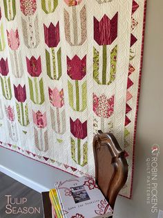 a quilted wall hanging next to a wooden chair