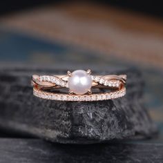 a pearl and diamond ring sitting on top of a rock