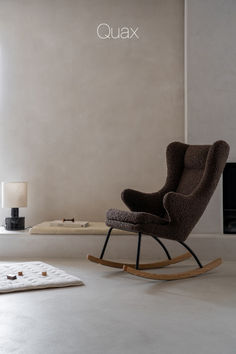 a rocking chair sitting in front of a window next to a rug on the floor