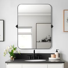 a bathroom vanity with a large mirror above it and two vases on the counter