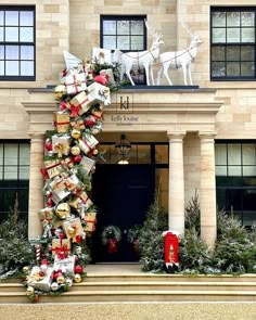 a large christmas tree with presents on it in front of a building that is decorated for the holiday season