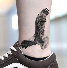 an eagle tattoo on the leg of a woman's lower body, with white and black stripes