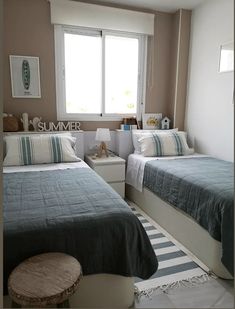 there are two beds in the room with blue and white blankets on them, next to a window