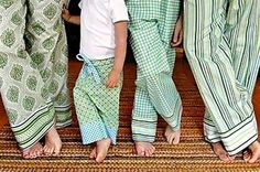 three young children standing next to each other in matching green and white pajamas on a rug