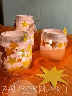 three jars with stars painted on them sitting on an orange table cloth and one has a yellow star