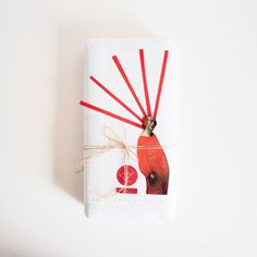 a white wrapping paper with a red bird on it's side and string attached to the top