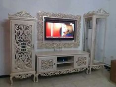 an ornate white entertainment center with a dog on the tv screen in front of it