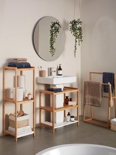 a white sink sitting under a mirror next to a wooden shelf filled with towels and other items