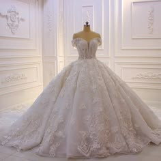 a wedding dress on display in a white room