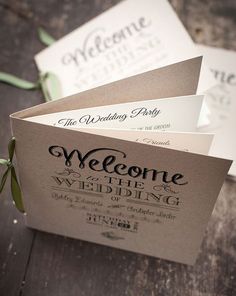 two wedding programs sitting on top of a wooden table