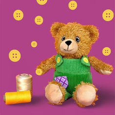 a brown teddy bear wearing overalls next to spool of thread and button holes