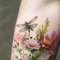 a woman's thigh with flowers and a dragonfly on it, painted in watercolor