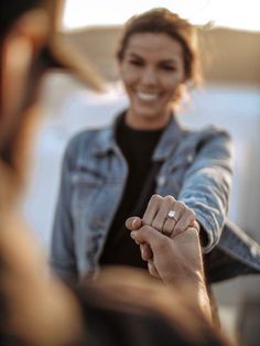 a woman holding the hand of another person with a smile on her face and arm