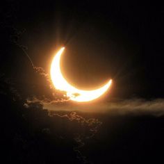 the moon is partially obscured by clouds as it passes in front of a dark sky