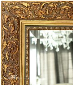 an ornate gold framed mirror in front of a chandelier