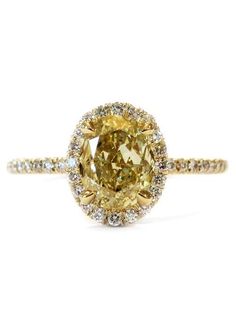 a fancy yellow diamond ring with white diamonds on the band and an oval center stone