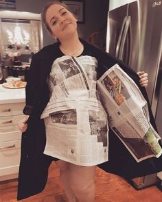 a woman standing in a kitchen holding a newspaper