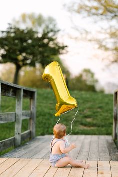 a baby sitting on the ground with a yellow balloon