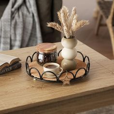 a wooden table topped with a metal tray filled with coffee cups and saucers next to an open book