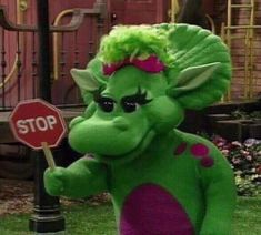 a green stuffed animal holding a stop sign