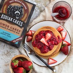 two plates with pancakes and strawberries next to a bag of kodia cakes powdered sugar