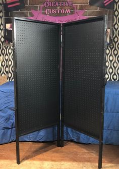 a black room divider sitting on top of a wooden floor next to a bed