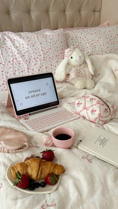 an open laptop computer sitting on top of a bed next to a plate of fruit