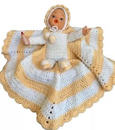 a crocheted baby doll laying on top of a yellow and white striped blanket