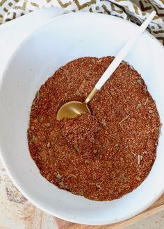 a white bowl filled with spices on top of a wooden cutting board next to a spoon