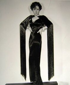 an old fashion photo of a woman in a black evening dress with long fringes