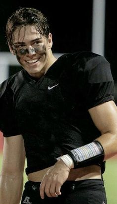 a football player with his face painted in the colors of black and white, smiles at the camera