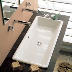 a white sink sitting on top of a wooden counter next to a mirror and towel rack